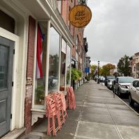 Exterior sign and outdoor seating- folded and dormant cuz rain at Little Rico in Hudson