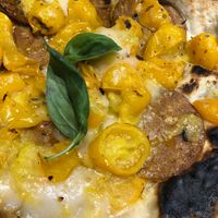 Pizza with vegan pepperoni, rice mozzarella, and yellow cherry tomatoes  at Assaje in Turin