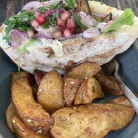 Pitta with aubergine, salad pomegranate and  seasoned potato wedges - ‘The Vegan One’ Uber pittas on menu.  at Hummel in Graz