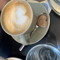 Oat cappuccino with accompanying biscuit  at LUSH Cafe in Munich