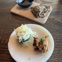 Shallot tart with tamarind sauce and fired shallot. Cucumber with apple, (vegan) comté cheese and pomegranate seeds. Homemade seed crackers and olive oil in the background.  at Funken Lodge in Longyearbyen