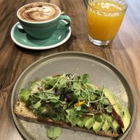 Capuchino con leche de avena, zumo de naranja y tostada de aguacate con tomate seco y levadura nutricional   at Malila Coffee in Valencia