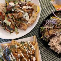 Left plate: ‘Vegan lust plate’ with stirfried veggies, crispy vegan chicken, crispy tempeh, brown rice, salad, vegan bacon, gyoza and extra sausages.    at TerraZen Centre in Amsterdam