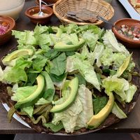 Vegan tlayuda with mole sauce topped with cactus, avocado, and lettuce at Tikua in Queretaro