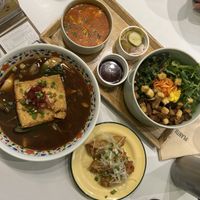 Clockwise from top: Tomato soft tofu stew, bibimbap with crumble tofu, signature warm noodle soup with pine mushrooms. Plus the sides.  at Plantude 플랜튜드 in Seoul