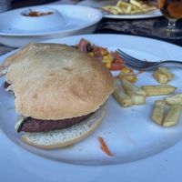 La burguer empezada, viene con cebolla caramelizada, calabacín y algo más acompañada de patatas y ensalada at El Chili M&M in Benasque