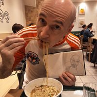 Me eating ramen in T's holding a sketch I did of myself from a photo of me eating ramen in T's.  at T's Tantan - Tokyo JR Station in Tokyo