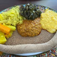 From left to right: alicha potatoes and carrot, cabbage, gomen (collards), alicha wot (yellow split peas), and misir wot (berbere lentils) in the middle, on injera  at Ethio Beans Ethiopian Restaurant and Cafe in Carol Stream