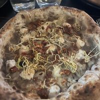 Pizza Torrefiel con salsa de setas, queso vegano, cebolla, tomate seco y crujiente de puerro.  at Pizzeria Km0 in Valencia