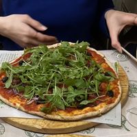 Pizza con tomate seco, cebolla roja, aceitunas y rúcula   at Pizzería Comes in Toledo