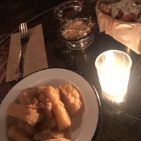 Yuga Frita - golden fried yuga topped with tangy and spicy coleslaw garnished with bacon bits and microgreens 
  at The Witches Brew in West Hempstead