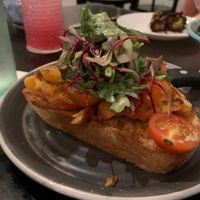 Seasonal sourdough toast with vegan cheese, roasted peaches, tomatoes, and a bed of dressed greens  at Down Island Gulf Seafood Restaurant in Santa Rosa Beach
