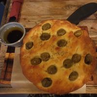 Focaccia Pugliese: Focaccia with olives served with olive oil and balsamic vinegar at Ortica Italian Plant Based in Urmston