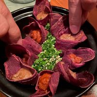 a delightful combination of crispy purple potato curls paired with creamy edamame dip and a refreshing tomato-onion salsa at Cuca in Jimbaran