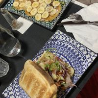 Vegan pancakes with maple syrup and banana. Hummus toast with veggies.   at Caffè dell'Arte Specialty Coffee in Cagliari