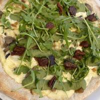 Pizza pestifera (mozzarella, basil pesto, caramelized onion, mushrooms, dried tomatoes and arugula).  at Humus Vegan Tenerife in Tenerife