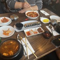 Korean tofu stew in front left, tteokbokki on the further side of the table, vegan bibimbap on the right side. Vegan kimbap in the middle, and yellow turnip kimchi.  at Korelee in Ankara