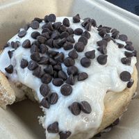 Roll with orange icing and chocolate chips (missing one bite).  at Cinnaholic in Raleigh