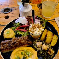 Onion focaccia, Cajun potatoes, a 7-spice veggie patty with house sauce, spinach with smoked tofu, pumpkin velouté with salted whipped cream, and a yellow vegetable purée. at Hododa in Marseille