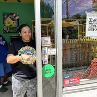 Chef Lulu adding Happy Cow sticker to window!   at Casa Borinqueña in San Francisco