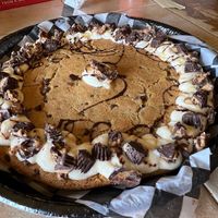 Cookie cake with cream cheese frosting, peanut butter cups, and caramel & chocolate drizzle.   at Cinnaholic in Carmel