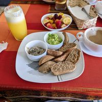 Vegan breakfast ($4.5) including bread, guacamole, mushroom spread, bowl of fruit, juice of your choice, and a coffee with plant milk. at Panaderia Taita in Cuenca
