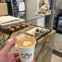 Flat white on oat with front counter in background  at OSLO in Amsterdam