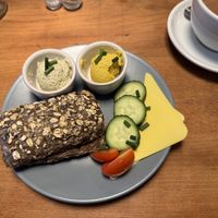 Ein kerniges Schwarzbrotbrötchen mit zwei veganen Aufstrichen: Mango-Papaya und Bärlauch-Senf. Dazu Gurkenscheiben, Cherrytomaten, zwei Scheiben veganer Käse.  at Veganes Café im Powerhouse  in Erftstadt