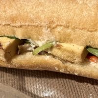 Tofu, cashew creme, mushroom, zucchini, and red bell pepper sandwich sitting on its takeaway wrapping   at Atelier Dulce Amarui in Cluj-napoca