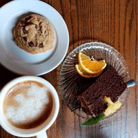 Chocolate cake with pineapple sauce, oat milk latte and a chocolate chip cookie.  at Trumpet Blossom Cafe in Iowa City