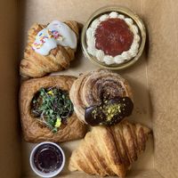 Left to right, then top to bottom: funfetti croissant, raspberry lemon cake, broccoli-ched’r danish, choco-pistachio cruffin, croissant with blueberry jam on the side  at Houlden's Rise Above in Tucson