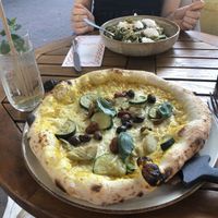 Pizza with yellow pepper base (bruh) and whipped “feta” pasta in the back (summer menu). I had an elderflower lemonade, my friends drink on the other hand...  at Vegitalian Pizza Bar in Utrecht