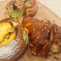 Savoury crossaint, tart and doughnut in background at Croix Croissant in Flemington
