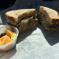 Sweet Curry Tempeh Sandwich with side of fruit at Harvest Thyme X-press in Gainesville