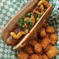 Sriracha Vegan Brat: Herbivorous Butcher Vegan Sriracha brat topped with sweet
chili mustard and green onion. Served on a pretzel bun and upgraded to include tots 💚  at Depot Tavern in Minneapolis