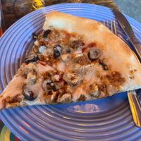 A slice of vegan pizza with myokos cheese, black olives, and vegan sausage  at Satchel's Pizza in Gainesville