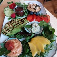 Large vegan breakfast with bread basket, hummus, vegetable spread, avocado, jam, fruit at Annegrete in Dusseldorf