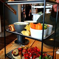 Picture shows an afternoon tea. 3 trays of food - bottom is an assortment of open sandwiches topped with antipasti and tomatoes with balsamic vinegar. Middle is a pot of crudites,  at Gray's Of Rothwell in Rothwell