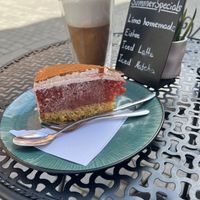 Apfel-Orangenkuchen mit einem Latte Macchiato auf einem kleinen Tischchen. at Portal Cafe in Uberlingen