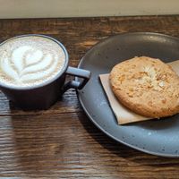 Oat milk cappuccino and almond and orange cookie at Origin Coffee in North West London