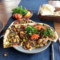 The serve you the pizza plus a side dish of lemon, parsley, and tomato to add to it. Amazingly flavorful! at Köşebaşı  in Goreme
