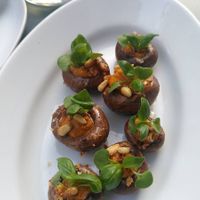 Marinated mushrooms filled with red pesto, topped with pine nuts and mini basil leaves at COR in Zurich