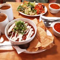 Chiliguacamole (bean chili, guacamole, vegan sour cream, and brown rice, served with tortilla chips), Breakfast Plate (tofu scramble, pico de gallo, tempeh bacon, toast, and salad), Americanos with homemade almond coconut milk, and complimentary gazpacho. Photo taken June 2018. at Resonance Cafe in Montreal