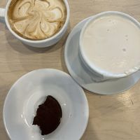 Top left: oat milk latte; right: London fog latte; bottom: half eaten chocolate tahini sandwich cookie  at Morning Bell Coffee Roasters in Ames