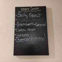 Die aktuellen, veganen Sorten stehen auch auf einer Tafel an der Wand in der Eisdiele at Glacë Manufaktur in Trier