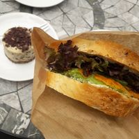 Sandwich with carrot, avocado, vegan cream cheese, lettuce and stracciatella cake in the back at MiiT in Riga