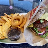 Mexi vegan burger- black bean burger with tomato sauce, avocado, mushrooms, lettuce, tomato, nachos, onion rings and aioli sauce. Comes with fries and vegan mayo and bbq sauce.  at Patricia's Gatekjøkken in Bardu