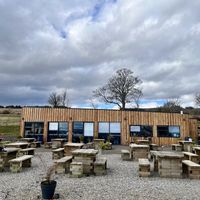 Exterior of building and outside tables + small play area   at Highland Farm Cafe in Dingwall