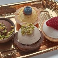 Mignon con frolle alla crema chantilly, crema al pistacchio e crema al mango. Il primo sulla destra é invece una tazzina al cioccolato con mousse al cioccolato e granella di pista at Pasticceria Dante in Piacenza