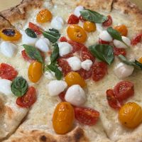 Pizza Reginella, with mozzarella cheese, two types of Pachino, "bocconcini"of burrata cheese and basil at Bottega di Rosaria in Siena